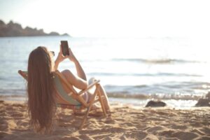 woman in white tank top sitting on white wooden chair on beach
