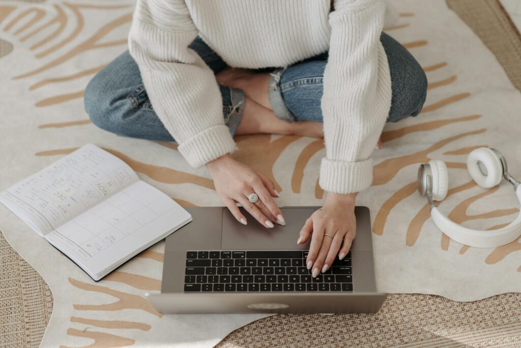 a woman cross sitting on floor typing on a laptop