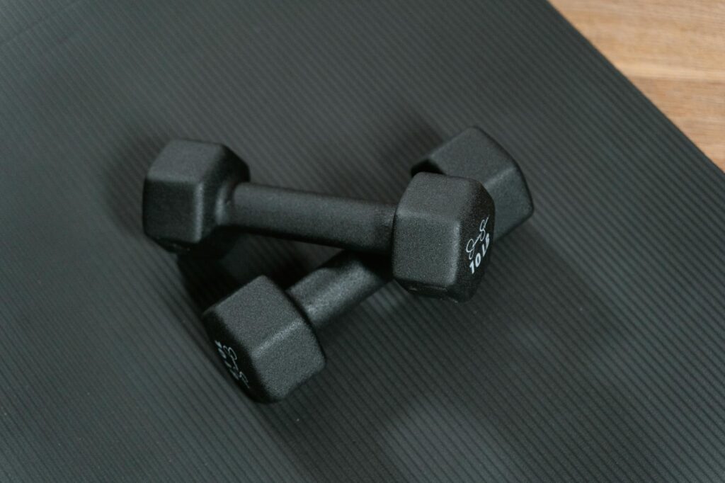 close up photo of two dumbbells on black yoga mat